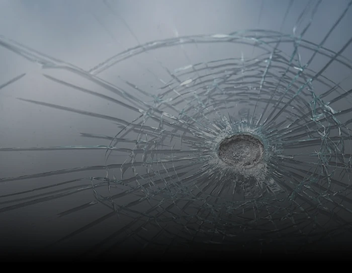 Shattered glass with a circular impact point and spiderweb cracks radiating outward.