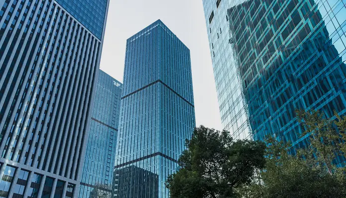 Modern glass skyscrapers in a business district with reflective blue office buildings and urban skyline.